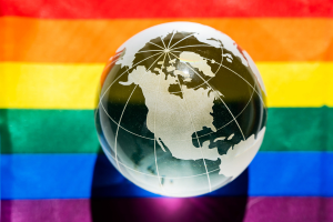 Gray globe imposed over rainbow Pride flag